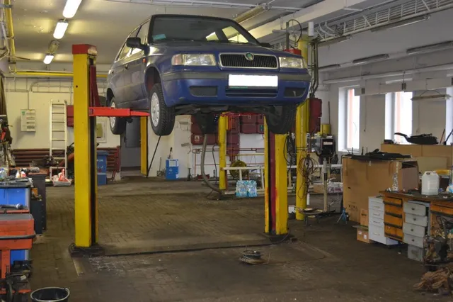Osobní automobil zvednutý na dvoustojanovém zvedáku v dílně