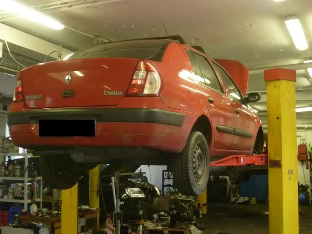 Červený hatchback na zvedáku zezadu, v pozadí vybavení dílny