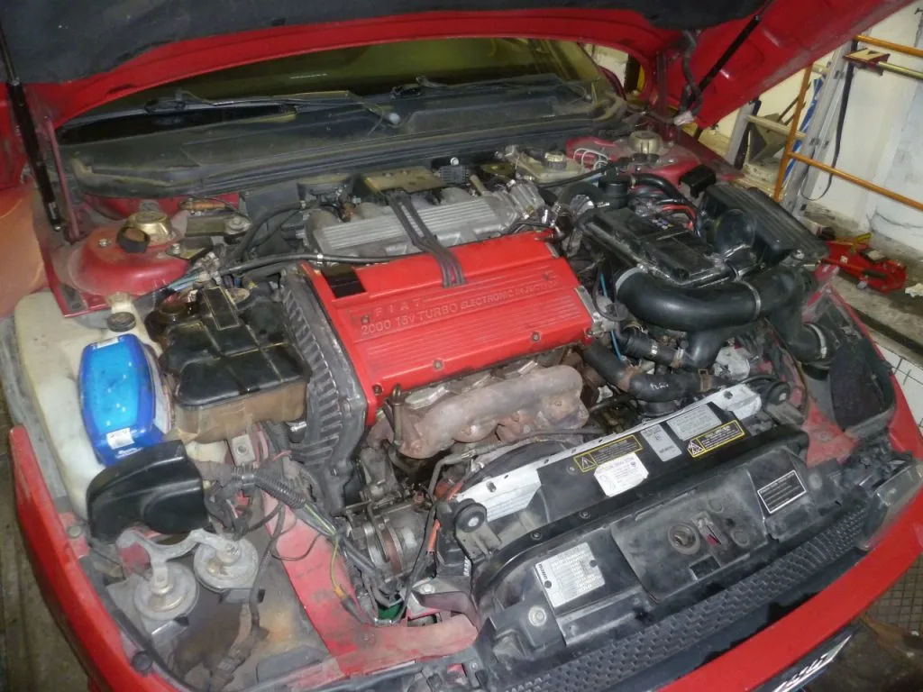Otevřený motorový prostor červeného vozu při práci v dílně