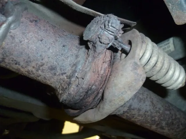 Detail zkorodovaného výfukového potrubí a pružiny pod vozem